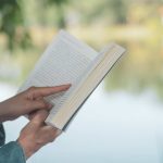 close up of a book being read by a pond