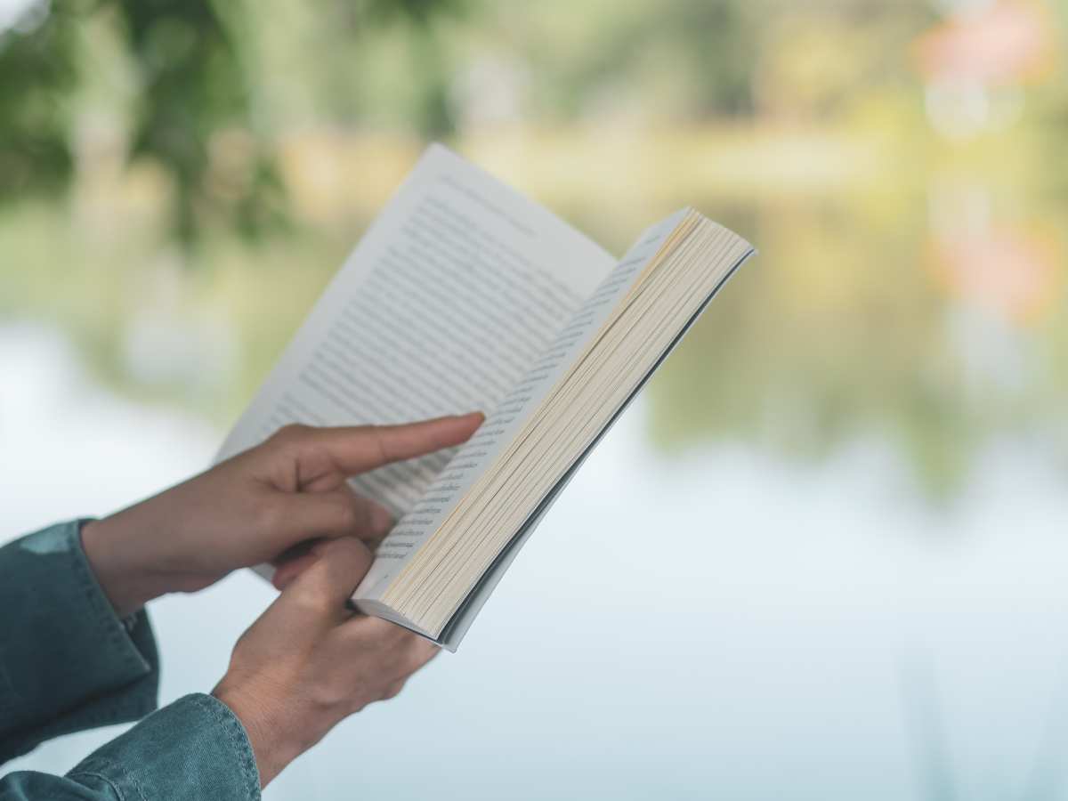 close up of a book being read by a pond