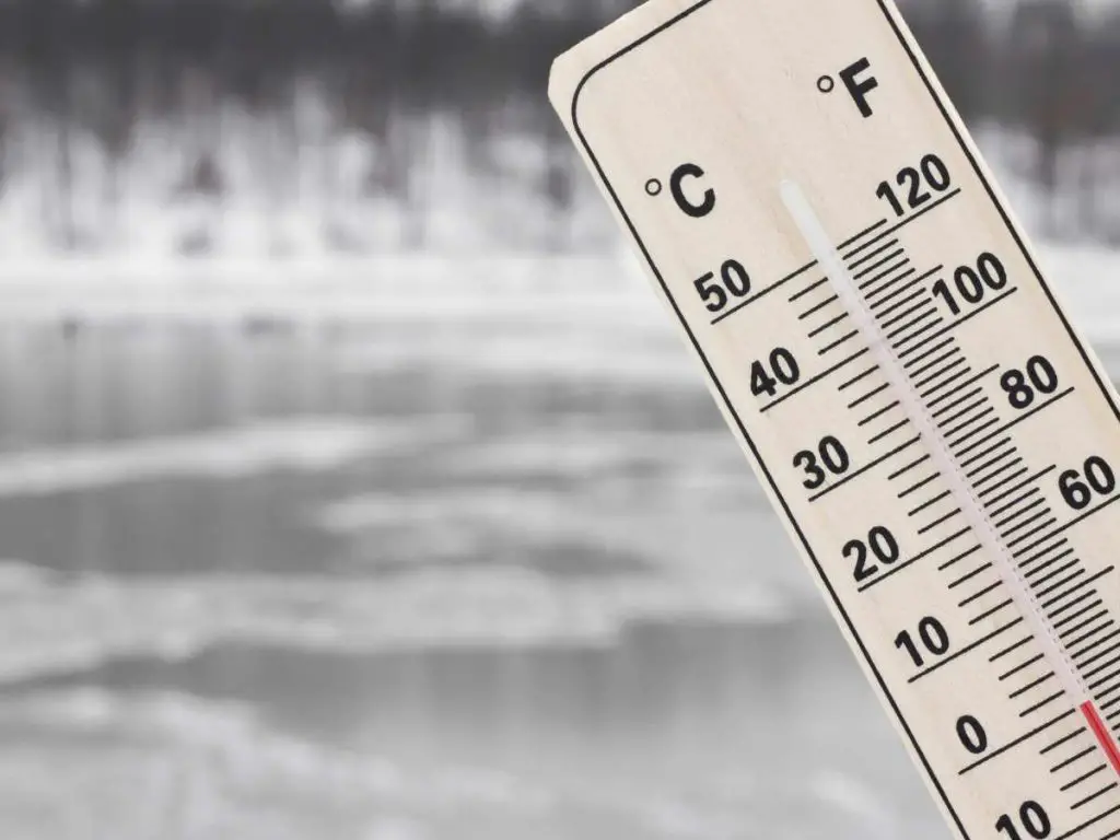 frozen lake in the background with a thermometer in the foreground